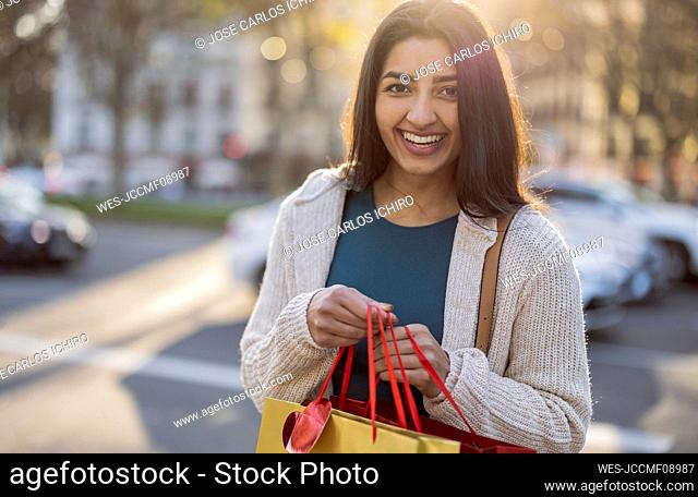 Happy young woman with shopping bags on sunny day