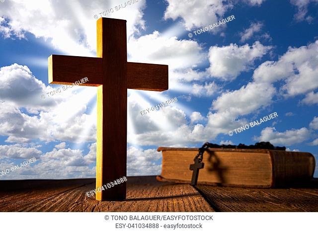 Christian wood cross on blue sky wooden made with Bible and rosary beads