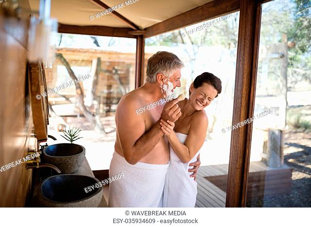 Smiling couple having fun while shaving in cottage
