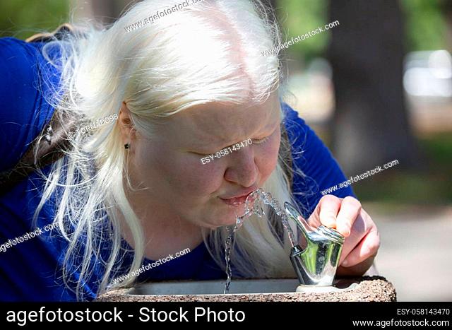 Close up of a woman drinking from a water fountain outside