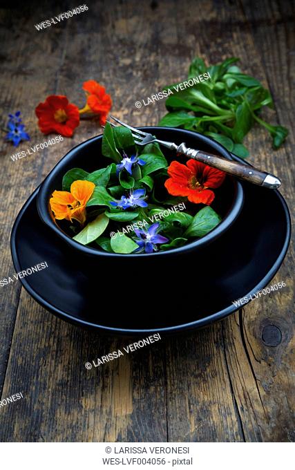 Bowl of lamb's lettuce with blossoms of borage and Indian cress
