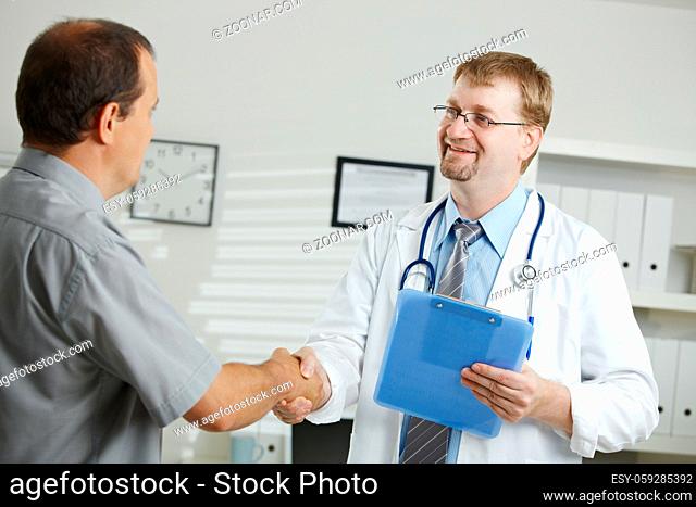 Medical office - middle-aged male doctor greeting patient, shaking hands