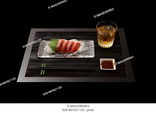 Sashimi on plate with whisky on table