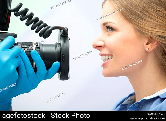 Dentist with camera making shots of patients smile after treatment. Special camera with flash ring shadowless