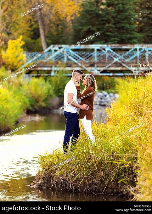 Husband and wife spending quality time together outdoors near a stream in a city park; Edmonton, Alberta, Canada