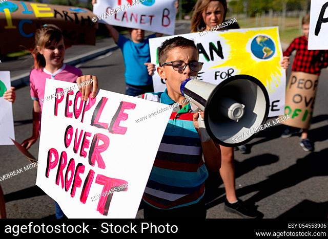 Front view of a group of Caucasain elementary school pupils on a protest march, carrying signs with environmental and conservation slogans on them