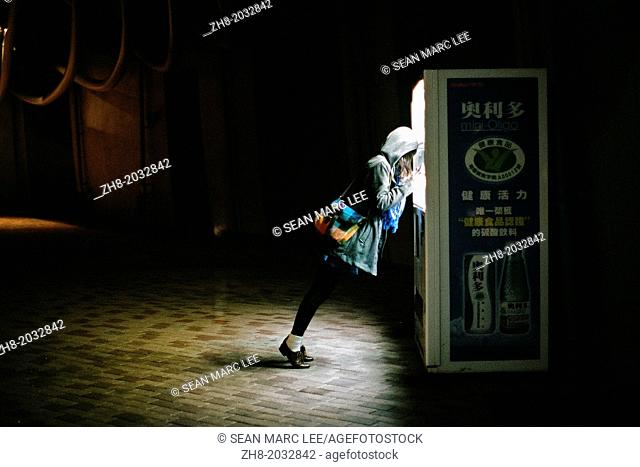 A girl leans on a vending machine at night in Kaohsiung, Taiwan