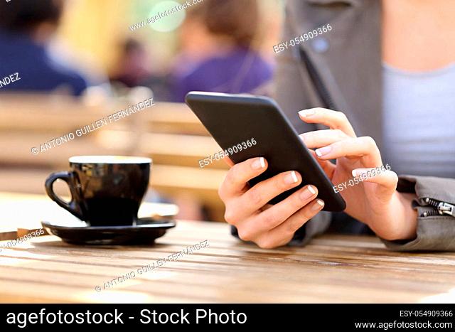 Close up of woman hands using her cell phone on a cafe terrace