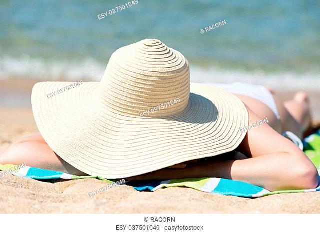 Relaxing young woman with sunhat enjoying the sun at beach