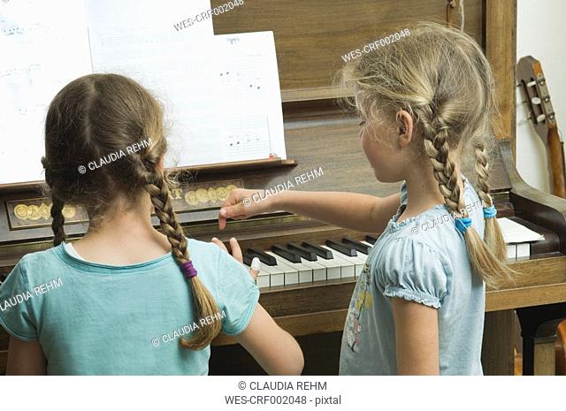 Germany, Bavaria, Two girls using piano and making music