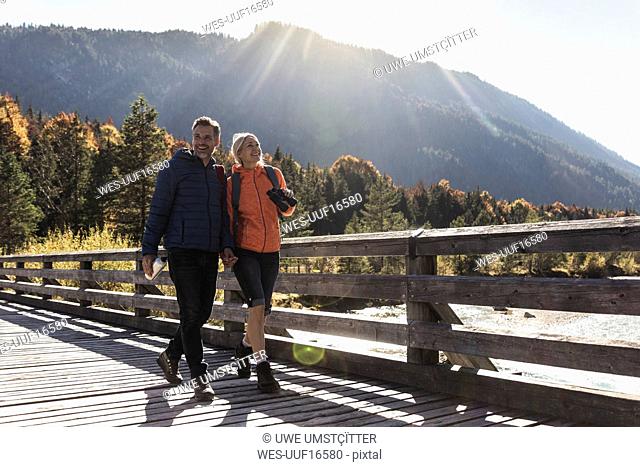 Austria, Alps, happy couple on a hiking trip crossing a bridge