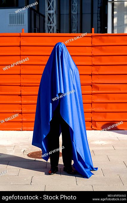 Anonymous man covered by blue cape