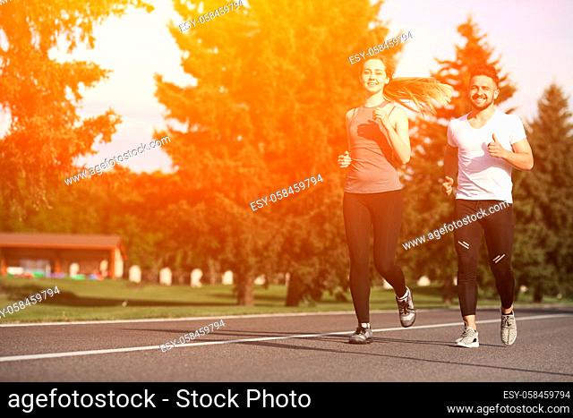 Young woman and man running along street or road. Happy couple doing sport and thinking about something positive. Toned