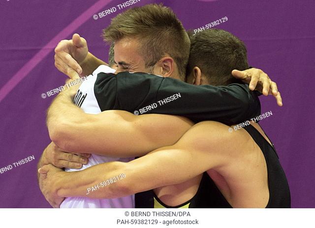 Germany's Martin Gromowski (R) and Kyrylo Sonn celebrate with a coach in the Trampoline - Men's Synchronised at the Baku 2015 European Games in National...