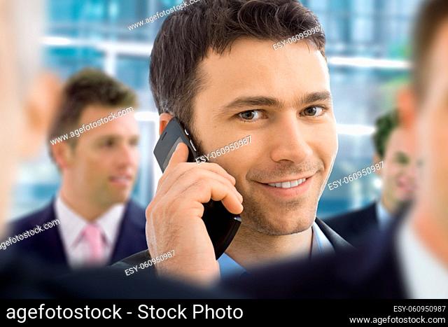 Closeup portrait of happy businessman talking on mobile in crowd in office lobby