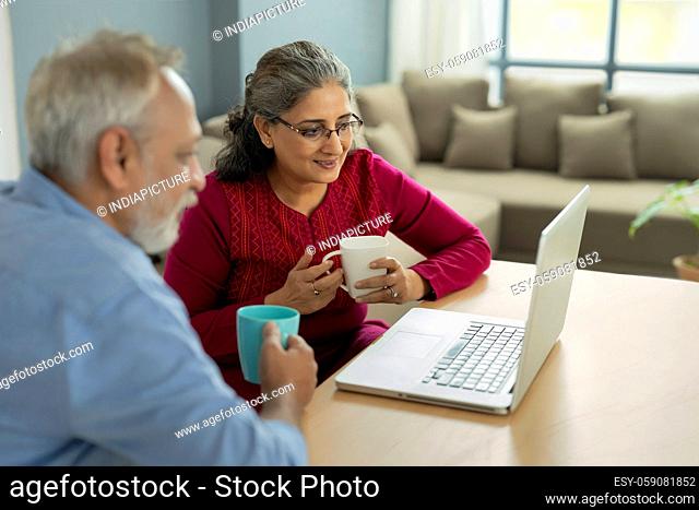 A SENIOR ADULT WOMAN AND HUSBAND LOOKING AT LAPTOP TOGETHER