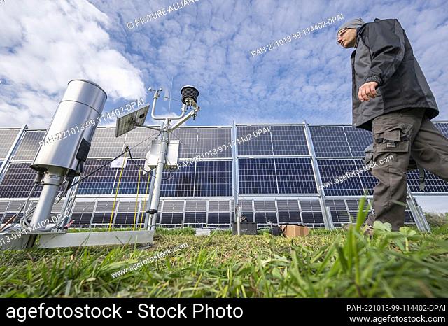 13 October 2022, Saxony, Dresden: Marc Heinrich of the German Meteorological Service DWD Potsdam walks to a mobile measuring station of the Agri Photovoltaic...