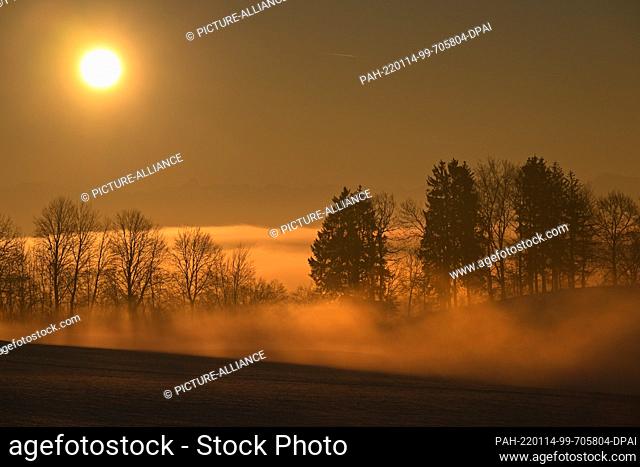14 January 2022, Baden-Wuerttemberg, Waldburg: The sun rises behind the Swiss Alps, while there is still fog in the lowlands of the Allgäu