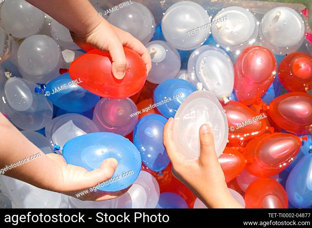 Close up of girl (6-7) and boy (4-5) playing with water balloons