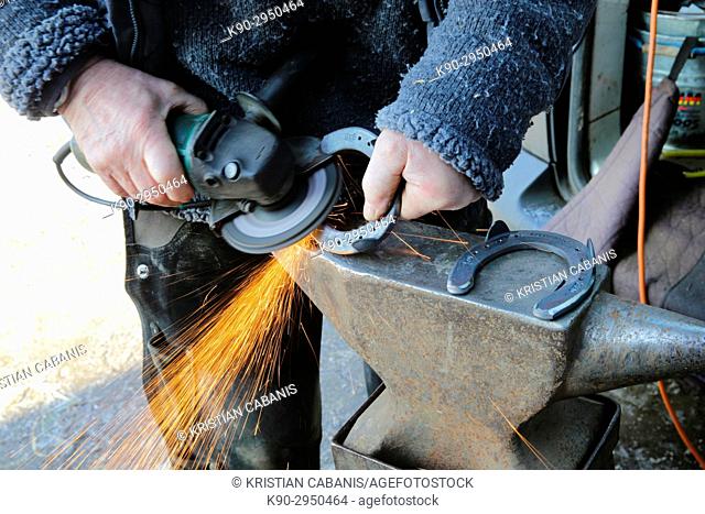 Blacksmith emitting sparks during grinding a horseshoe, Lennestadt, Siegerland, North-Rhein-Westphalia, Germany, Europe