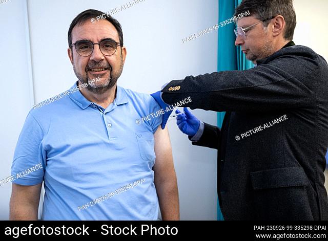 26 September 2023, Bavaria, Munich: Klaus Holetschek (l, CSU), Bavarian Minister of Health, gets a flu vaccination from Wolfgang Ritter