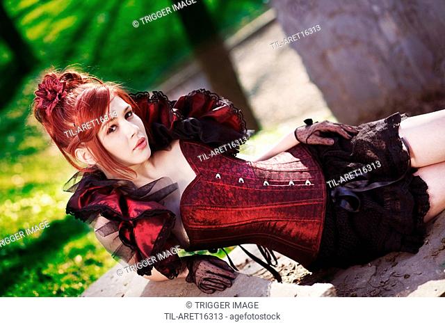 Redhead dressed in Victorian style sitting on stairs