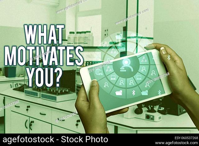 Text sign showing What Motivates Youquestion, Business idea know reasons why you want to wake up each morning Hands Holding A Mobile Phone In Laboratory Showing...