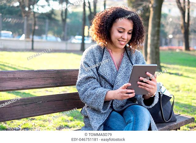 Black woman using application on tablet in the city park