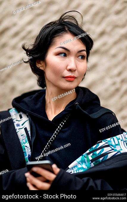 A young woman of eastern nationality with a phone in her hands in black clothes