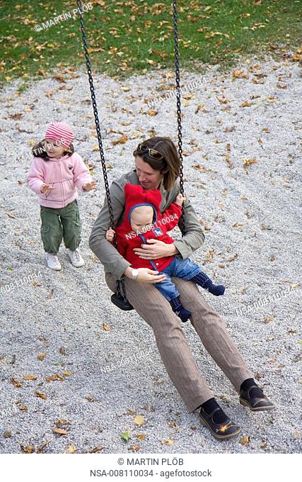mother with baby in arm on swing