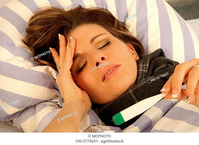 Eine junge Frau liegt mit Fieberthermometer krank im Bett, 2006 - Hamburg, Germany, 26/01/2006