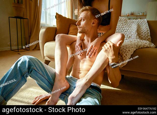 Erotic half dressed couple rest together in home living room. Young girlfriend putting leg on boyfriends shoulder. Dreaming people emotion and romantic...