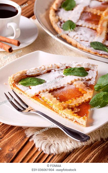 Piece of Italian tart with apricot jam and coffee on the table. Vertical