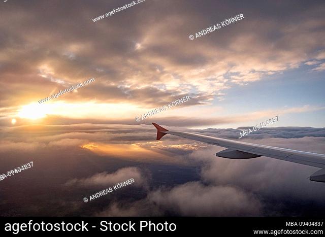 View from the window of an airplane at sunset on opening cloud cover and mainland
