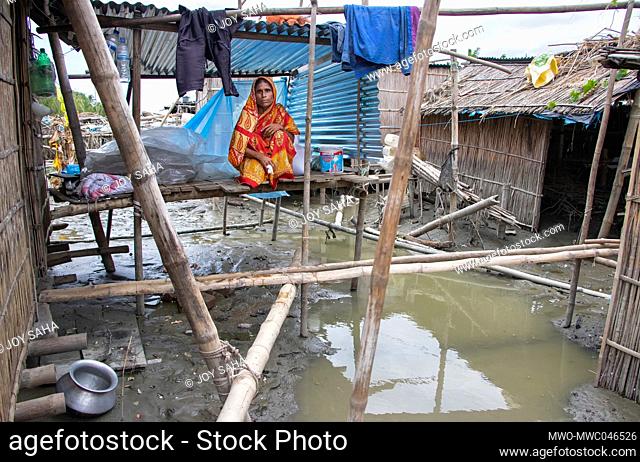 A woman stays inside a temporary makeshift hut as recent flood swept over the area and caused damage to the house, cattle and belongings in Munshiganj