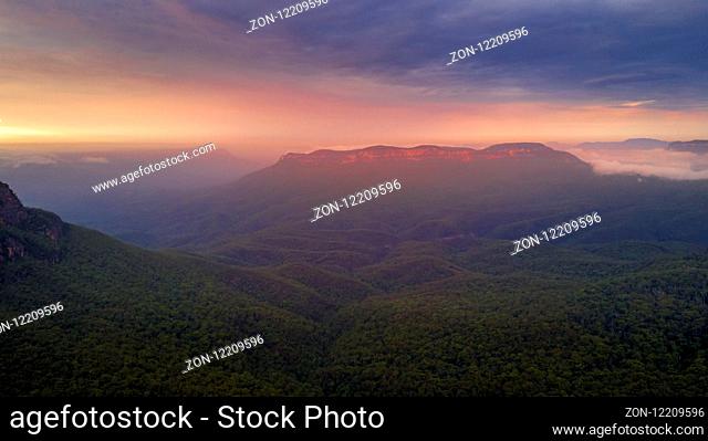 Beautiful sunrise over mist-filled Jamison Valley. In the distance Mt Solitary cliffs catch the warm light. Blue Mountains Australia