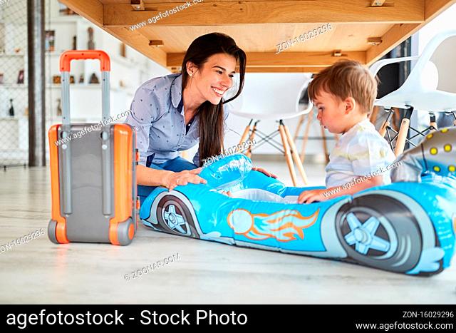 Mutter spielt mit Kind im aufblasbaren Auto als Rennwagen oder Schlauchboot