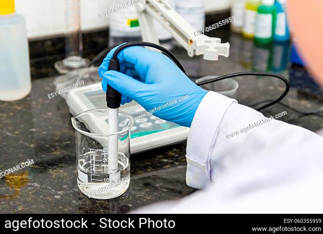 Woman hands performing pH test on pH meter electronic instrument for quality control in chemical industry