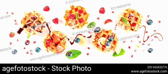 Belgian waffles with fresh fruit and syrup, shot from above on a white background