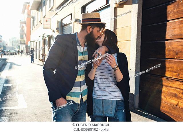 Romantic couple kissing on sunlit street