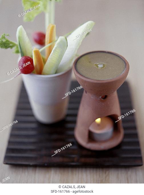Vegetables sticks in beaker, warm anchovy dip beside it