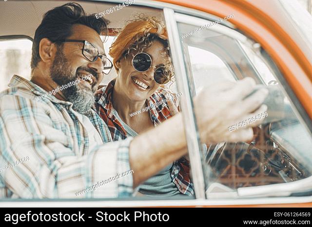 Happy couple having fun inside a car during travel adventure. Cheerful man and woman smiling and laughing a lot together