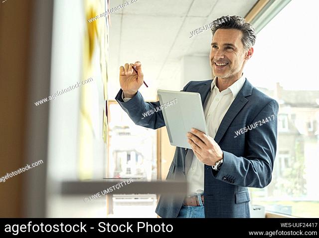 Smiling businessman with digital tablet working at office