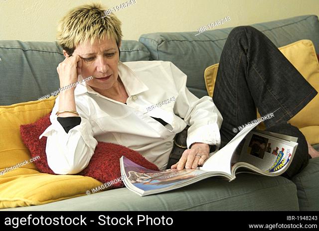 Woman lying on a sofa, reading a magazine