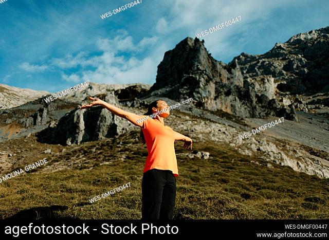 Hiker standing with arms outstretched against mountain at Cares Trail in Picos De Europe National Park, Asturias, Spain
