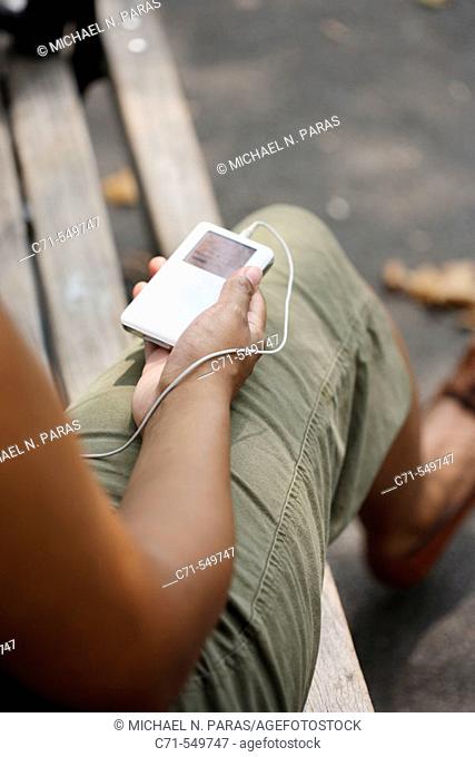 African-American woman holding ipod on park bench