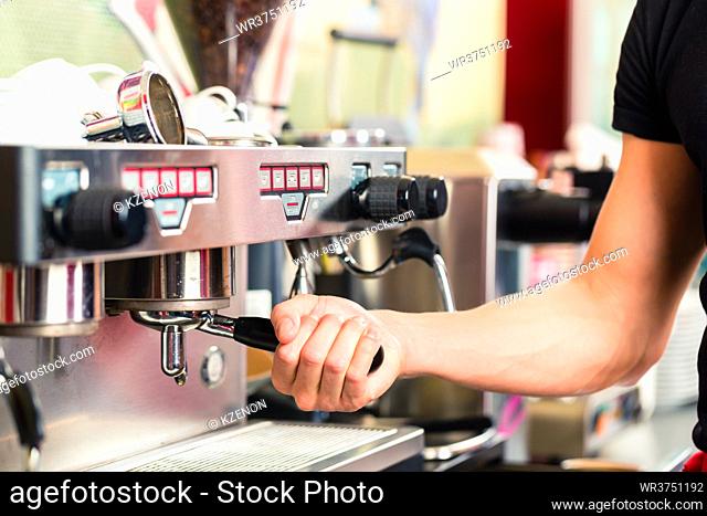 Barista using coffee machine or unit and preparing espresso or cappuccino in coffeehouse or shop