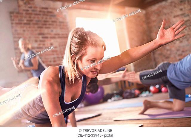 Young woman doing bird dog plank in exercise class gym studio