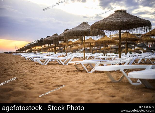 Beautiful colorful sunset over sun beds and umbrellas in Vilamoura, Algarve, Portugal, Europe