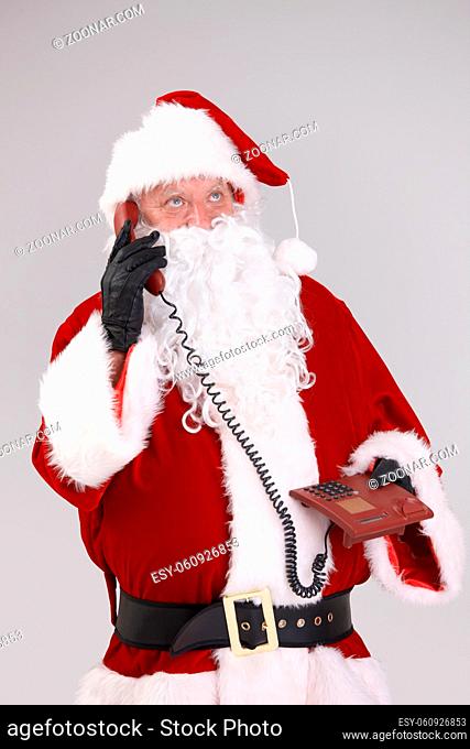Portrait of Santa on the phone, looking up, isolated on gray background